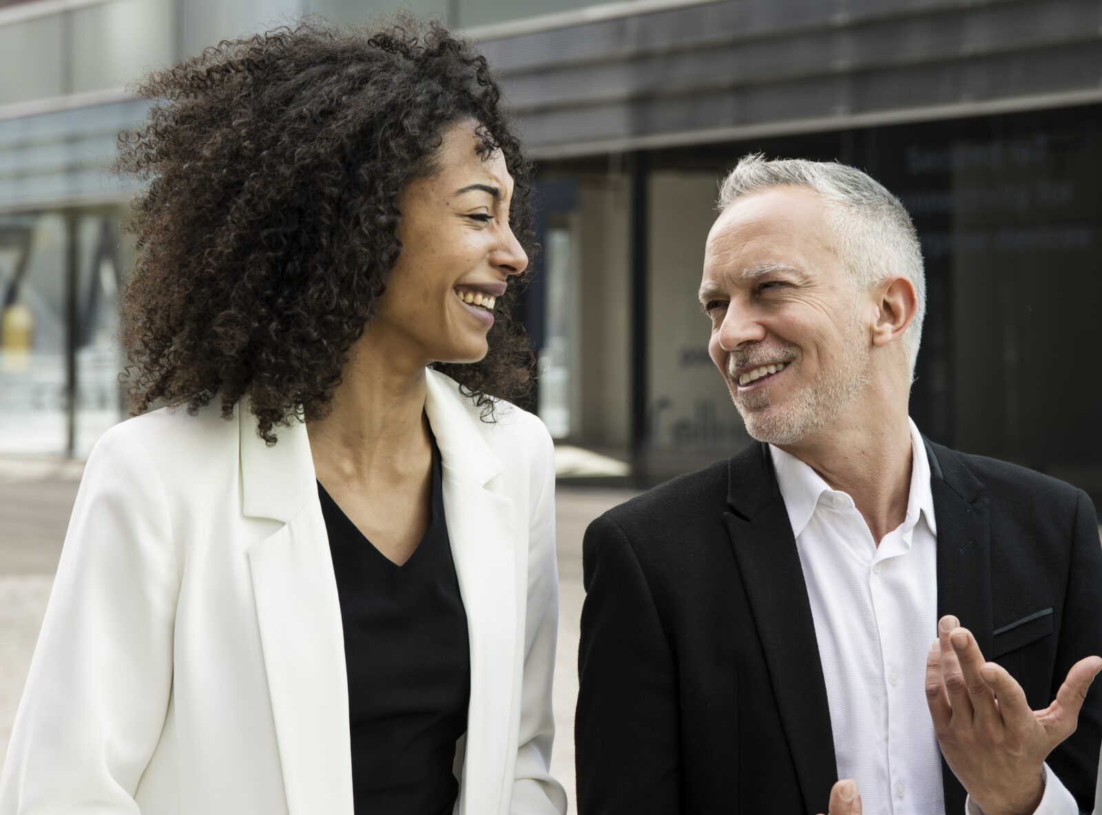 Businesswoman and businessman talking and smiling in the street.